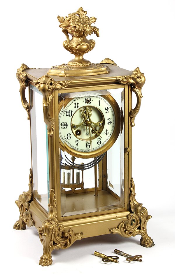 Gilbert Clock Co. crystal regulator clock: Gilbert Clock Co. crystal regulator clock, having an urn and floral finial surmounting the case with the four beveled glass panels containing an enameled dial with Arabic numerals and open escapement,