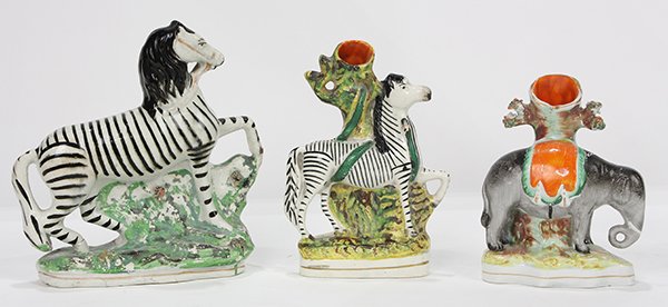 (lot of 3) Staffordshire figural groups, consisting of: (lot of 3) Staffordshire figural groups, consisting of an elephant with an orange blanket spill vase, a zebra in front of a tree spill vase, and, a prancing striped horse figure, largest 8"h x 7.5"w x