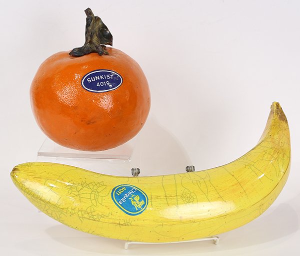 Sculptures by Karen Shapiro: (lot of 2) Karen Shapiro (American, b. 1947), Giant Banana and Orange, ceramic sculptures, stamped "K" on bottom, largest overall: 8.5"h x 17"w x 3.5"d.