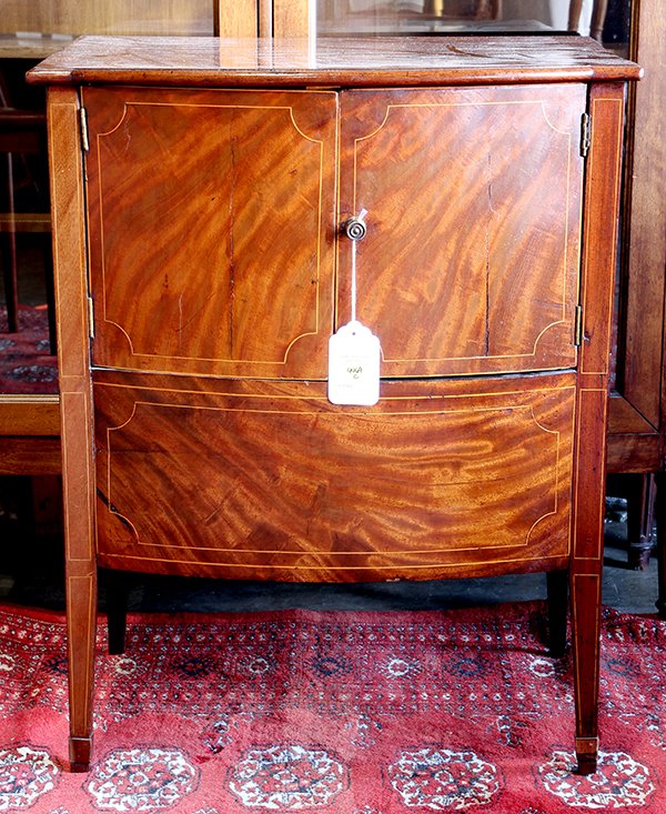 George III bedside commode circa 1810: George III bedside commode circa 1810, executed in highly figured mahogany with string inlay, the shaped top surmounting the bow front cabinet with two doors and the whole rising on tapering square le