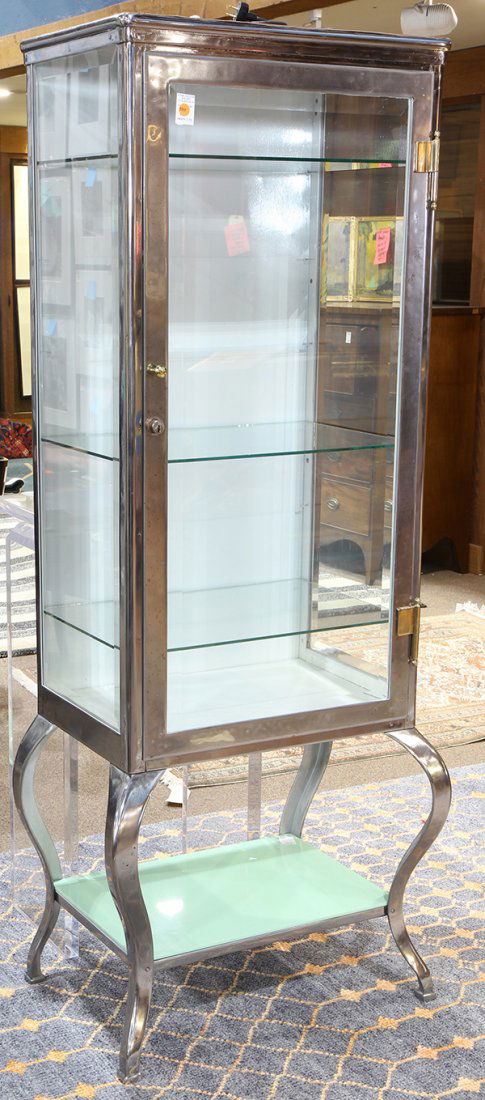 Mid-Century chrome medical cabinet: Mid-Century chrome medical cabinet, circa 1940, having a single beveled glass door opening to a fixed shelf interior, and rising on cabriole legs conjoined by a lower tier, 69.5"h x 28.5"w x 18"d