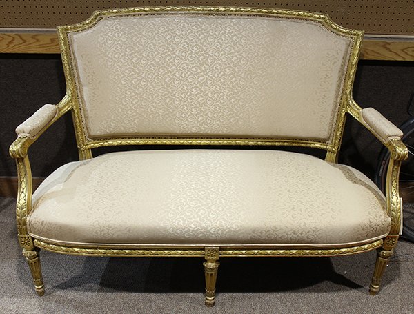 Louis XVI style giltwood settee: Louis XVI style giltwood settee, having a carved and shaped crestrail, above the upholstered seat and back, and rising on fluted and tapered legs, 39"h x 55"w x 19"d. Provenance: Property from the col