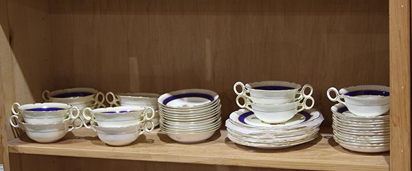 One shelf containing a partial service of Shelley: One shelf containing a partial service of Shelley porcelain, having a cobalt band at the the rim with gilt embellishment and centering a hand painted floral spray, consisting of (11) consume bowls, (1