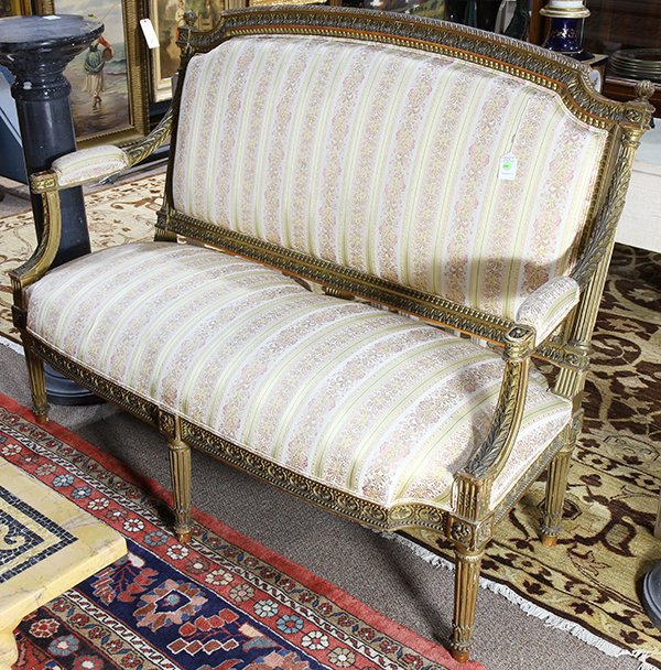 Paint decorated and parcel gilt settee in the Regency: Paint decorated and parcel gilt settee in the Regency taste, circa 1880, having a carved crest flanked by finials leading to the acanthus carved arms, the seat and back upholstered in damask, and risi