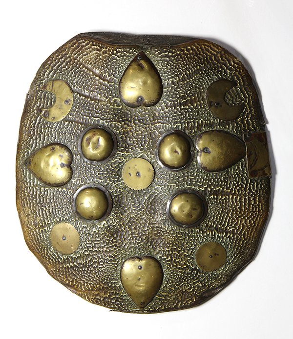 Indo-Persian (Dhal) parrying shield or Madu: Indo-Persian (Dhal) parrying shield or Madu, 18th century, executed in turtle shell with applied brass bosses in the form of hearts and crescent moons, the interior with rings for straps, 17"h x 16"w