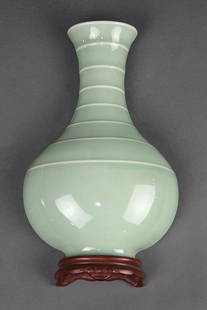 Chinese Celadon Wall Vase: Chinese celadon glazed porcelain wall vase, with a ribbed trumpet neck above a round body, the base in the form of a wood stand, the underside with an apocryphal Qianlong mark, 10.75"h. Provenance: pr