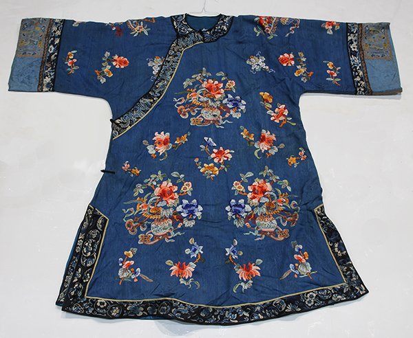Chinese Woman's Blue Damask Robe: Chinese women's blue robe, the damask blue ground woven with prunus on a honeycomb ground, embroidered with satin stitched bright bouquets of flowers and floral sprigs, bands at the neckline and sleev