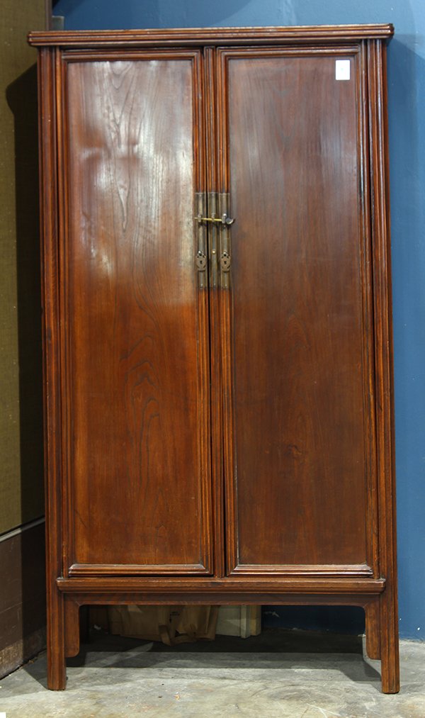 Chinese Clothing Cabinet: Chinese elm wood clothing cabinet, 19th/20th century, fronted by hinged double doors and central stiles, the interior centered by a row of two drawers, raised on straight supports, carved with raised
