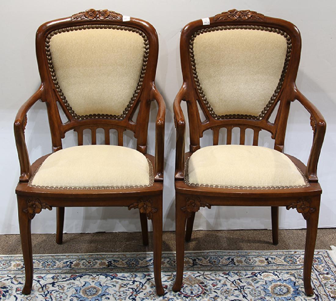 Pair of Art Nouveau style carved fauteuils: Pair of Art Nouveau style carved fauteuils, each having a floral carved crest above the shield form back with brass nail head trim, the highly stylized arms with floral reserves, and rising on outswep