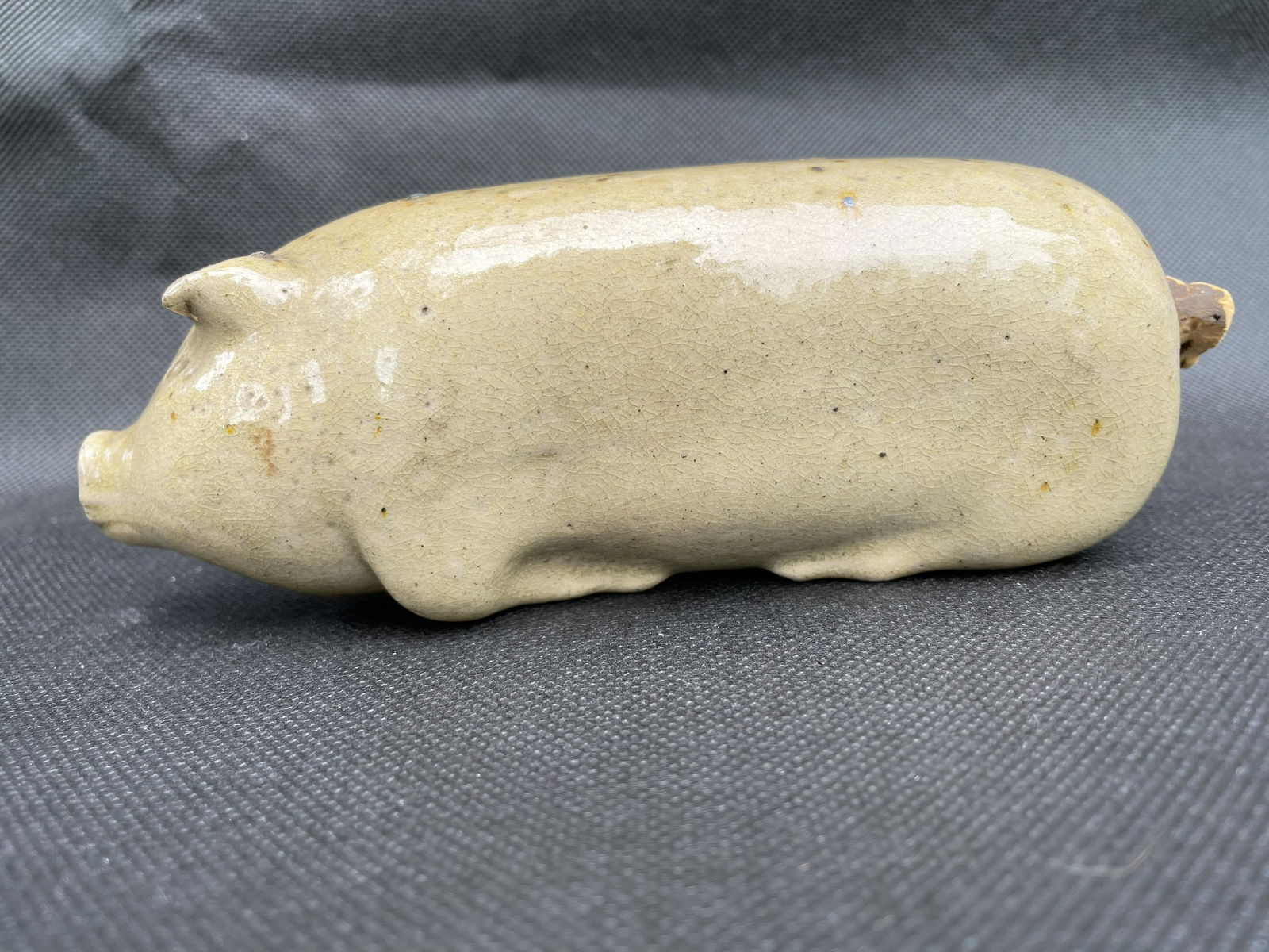 Stoneware Pig Flask: Salt-glazed stoneware pig flask with a slip color somewhere between yellow and gray. Excellent condition aside from the spout has an old 1/2" x 1/4" chunk missing. 6 3/8" in length. Probably Mid-Weste
