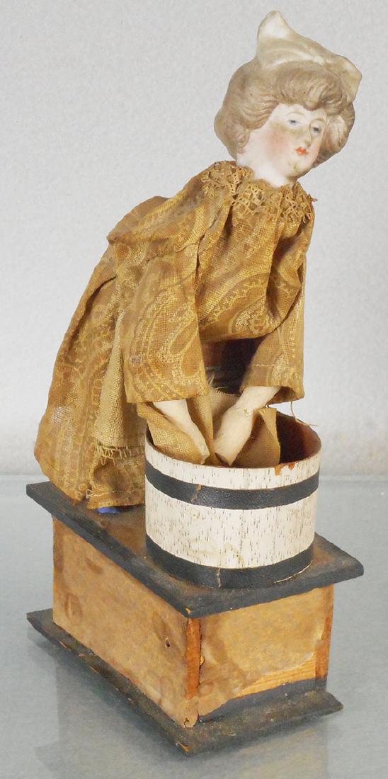 WASHER WOMAN SQUEAK TOY: bisque head on dressed wooden washer woman, litho paper on wood platform, squeaker not working, 8 in tall, C6.