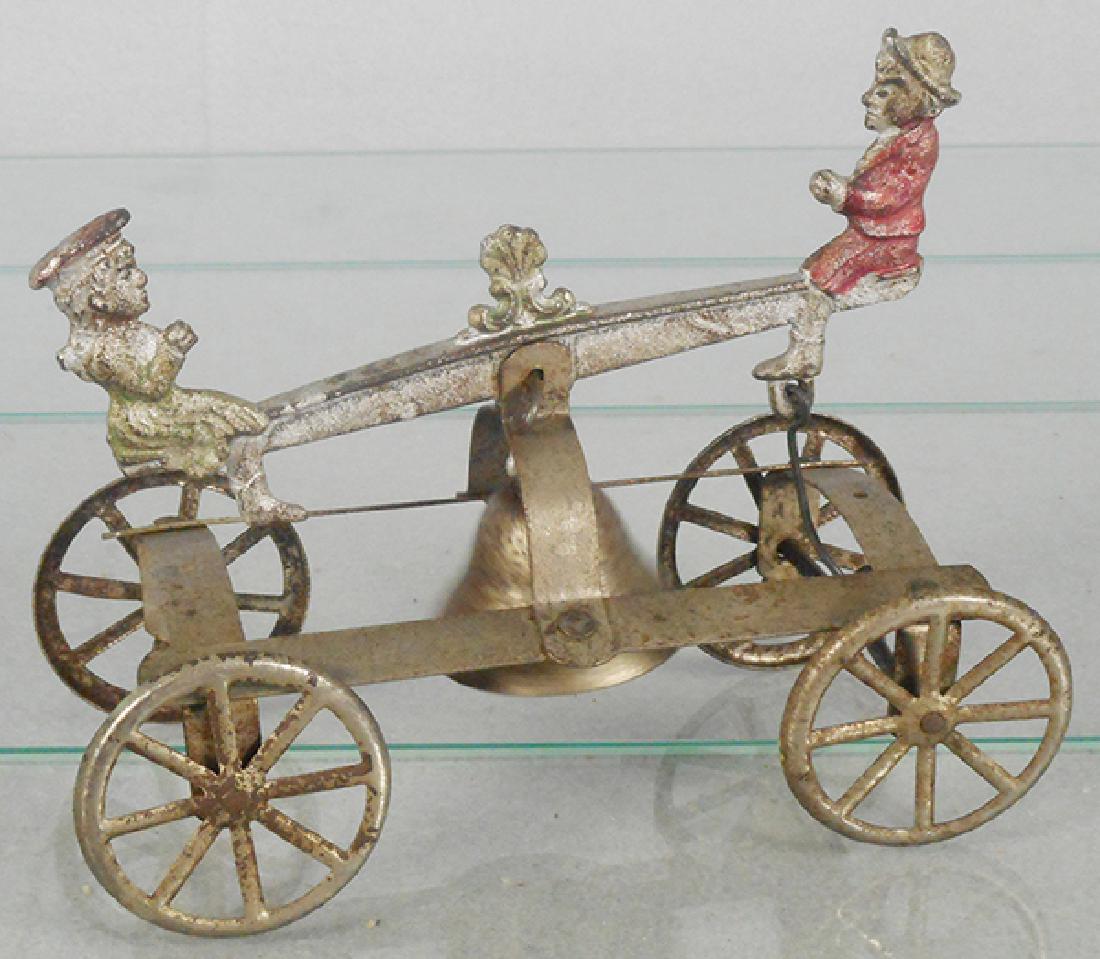 GONG BELL BOY & GIRL ON SEE SAW: cast iron & tin, paint worn on cast iron, tin parts have surface oxidation, 6 1/4 in long, C5.