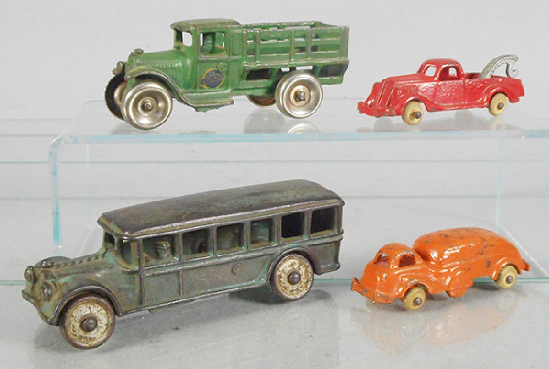 4 CAST IRON VEHICLES: Arcade Stake Truck, green, nickel wheels, 5 in long, Hubley 2303 Streamlined Truck, orange, 4 in long, white rubber tires worn, 1 loose, Hubley Wrecker, red, 4 in long, white rubber tires, Arcade Fage
