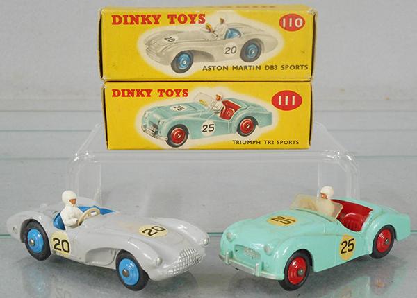 2 DINKY RACERS: 110 Aston Martin, gray w/blue hub caps, 111 Triumph, turquoise w/red hubs, orig boxes have correct color dots, C8-9.