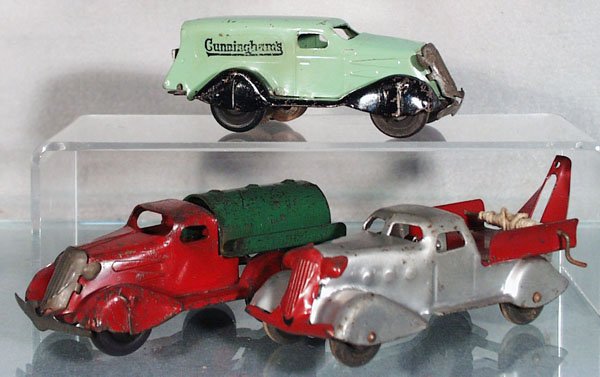 3 WYANDOTTE TRUCKS: painted pressed steel, 5 1/4 in long, wooden wheels, Cunningham's Van, friction working, Tank Truck, missing fly wheel, Tow Truck, missing hook, 2 have tarnished grilles, C4-5.