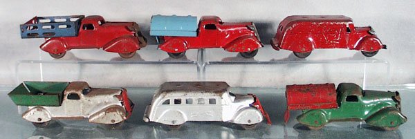 6 MARX TRUCKS: painted pressed steel, Express Truck, Petrol Tank Truck, Coast to Coast Moving Van, Dump Truck, Greyhound Bus, Petrol Tank Truck, all have playwear & tarnished trim, wooden wheels, 6" long, C3-5.