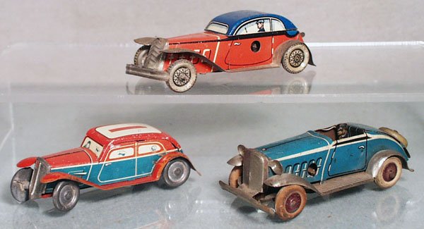 3 TIN AUTOS: litho tin, Sedan, 3 1/4" long, red & blue, Coupe, 3 1/2" long, fenders & running boards have wear, windup working, Roadster, made in Germany, 4" long, windup not working, C4-5.