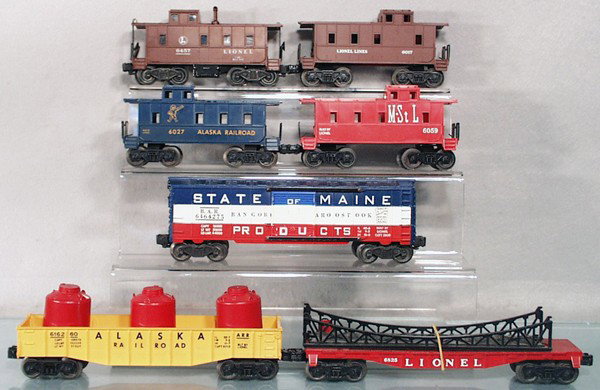 7 LIONEL FREIGHT CARS: O ga, 6457 caboose, 6017 caboose, 6027 Alaska caboose, 6059 caboose, 6464-275 SOM box car, w/2 chipped steps, 6162-60 Alaska gondola w/canisters, 6825 flat w/bridge, C5-7.