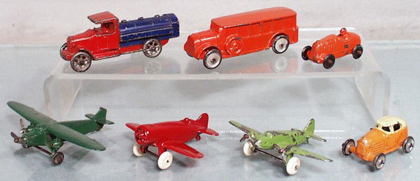 7 CAW NOVELTY VEHICLES: slush die cast, red & blue Tank Truck, 3 1/2" long, orange Bus, 3 1/2" long, orange Racer, 2" long, green Trimotor, 4 1/2" wingspan, missing 1 propeller, red Gee Bee Plane, 3" wingspan, restored, gree