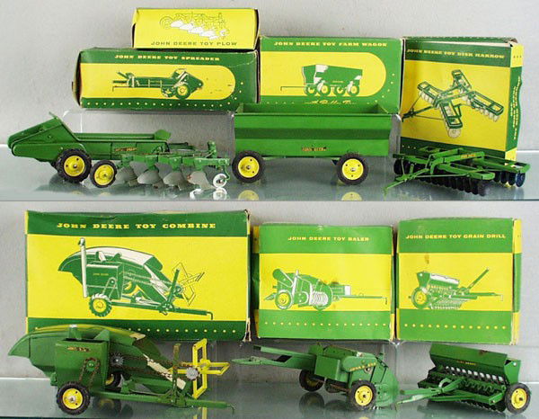 7 ESKA JOHN DEERE FARM TOYS: painted pressed steel, Grain Driller, Bailer, Plow, Disk Harrow, Spreader, Wagon, Combine, all have minor surface rust, orig boxes minor wear, C5-7.