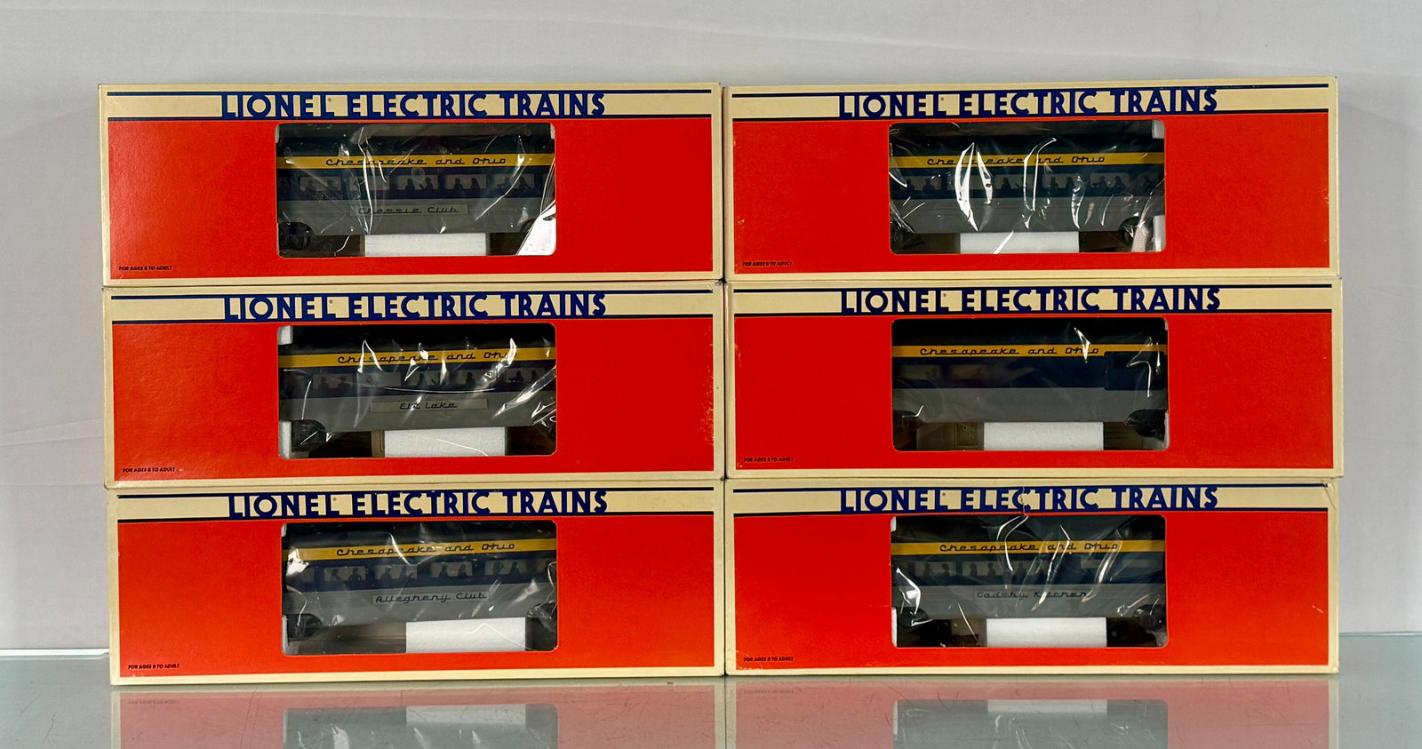 6 Lionel Chesapeake & Ohio O Gauge Aluminum Passenger Cars: A set of six Lionel Chesapeake & Ohio O Gauge aluminum passenger cars, each presented in its original red, white, and blue cardboard box with a clear plastic viewing window. The boxes are labeled