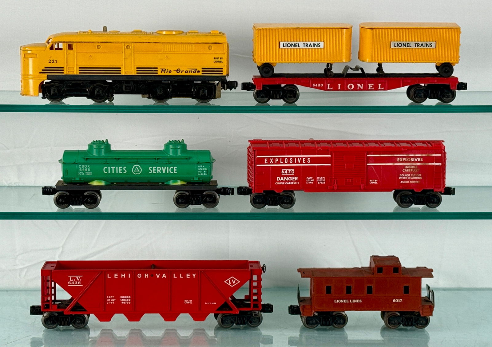 Lionel O-Gauge Trains Set: 221 Rio Grande Alco diesel, 6436 LV hopper, 6430 Flat with trailers, 6470 Exploding box car, 6465 Cities service tank car, 6017 Caboose, C5-7. 