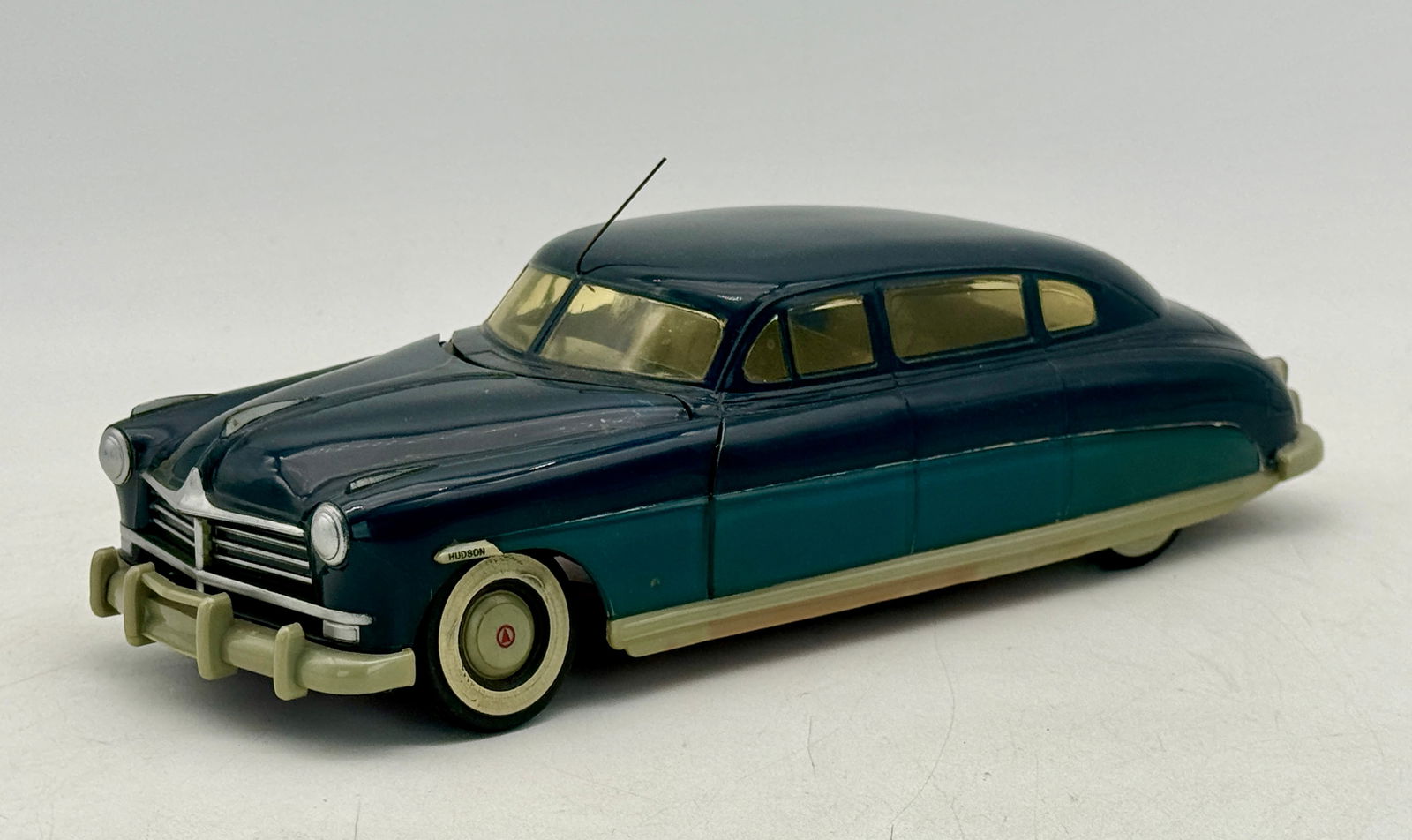 Hudson 1948-49 Commodore Sedan Promo: A dark blue and teal plastic toy car with beige bumpers and side skirts, featuring the inscription "HUDSON" above the front wheel, 13 inches long, C7-8.