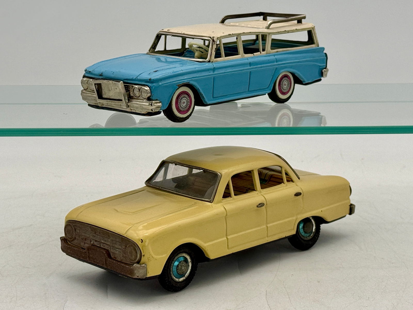 Two Japanese litho tin Toy cars: Alps 1960 Ford Falcon sedan 8 1/2 inches long with surface oxidation on trim, Bandai 1961 Rambler wagon, blue and white missing windshield plastic , friction working C6.
