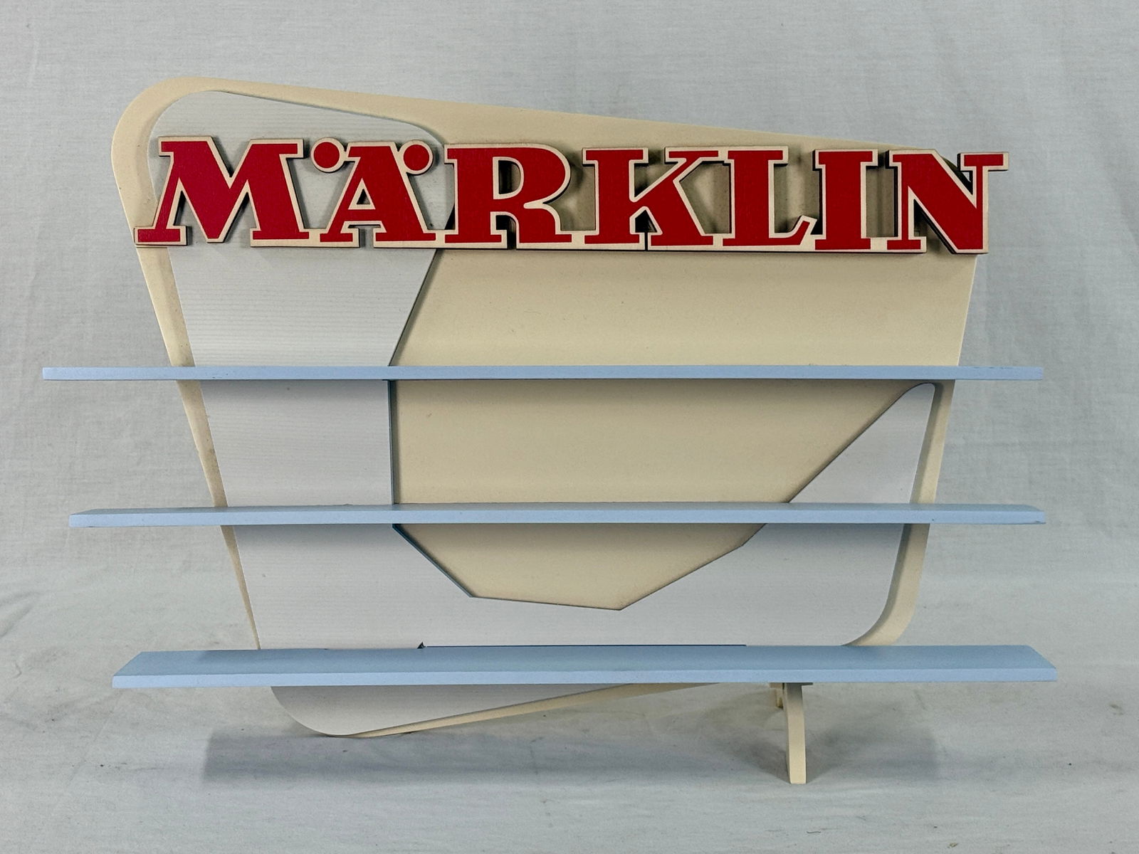 Marklin Decorative Display Showpiece with Three Shelves: A Marklin decorative display showpiece, model 19 224, featuring a yellow rear panel and foot, grey with white stripes upright rear panel, blue display surfaces, three blue shelves, and a red 'MARKLIN'