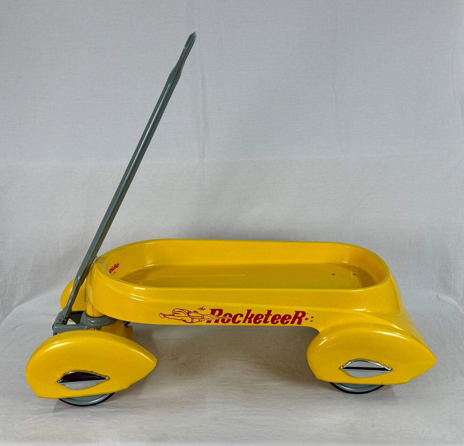 Glide Ride Rocketeer Yellow Sled: A yellow Rocketeer sled with a grey handle, featuring 'Glide Ride SACRAMENTO, CA' printed inside, a 'GR Glide Ride' winged logo on the front, and an embossed 'GR' logo on the floor Painted Press steel