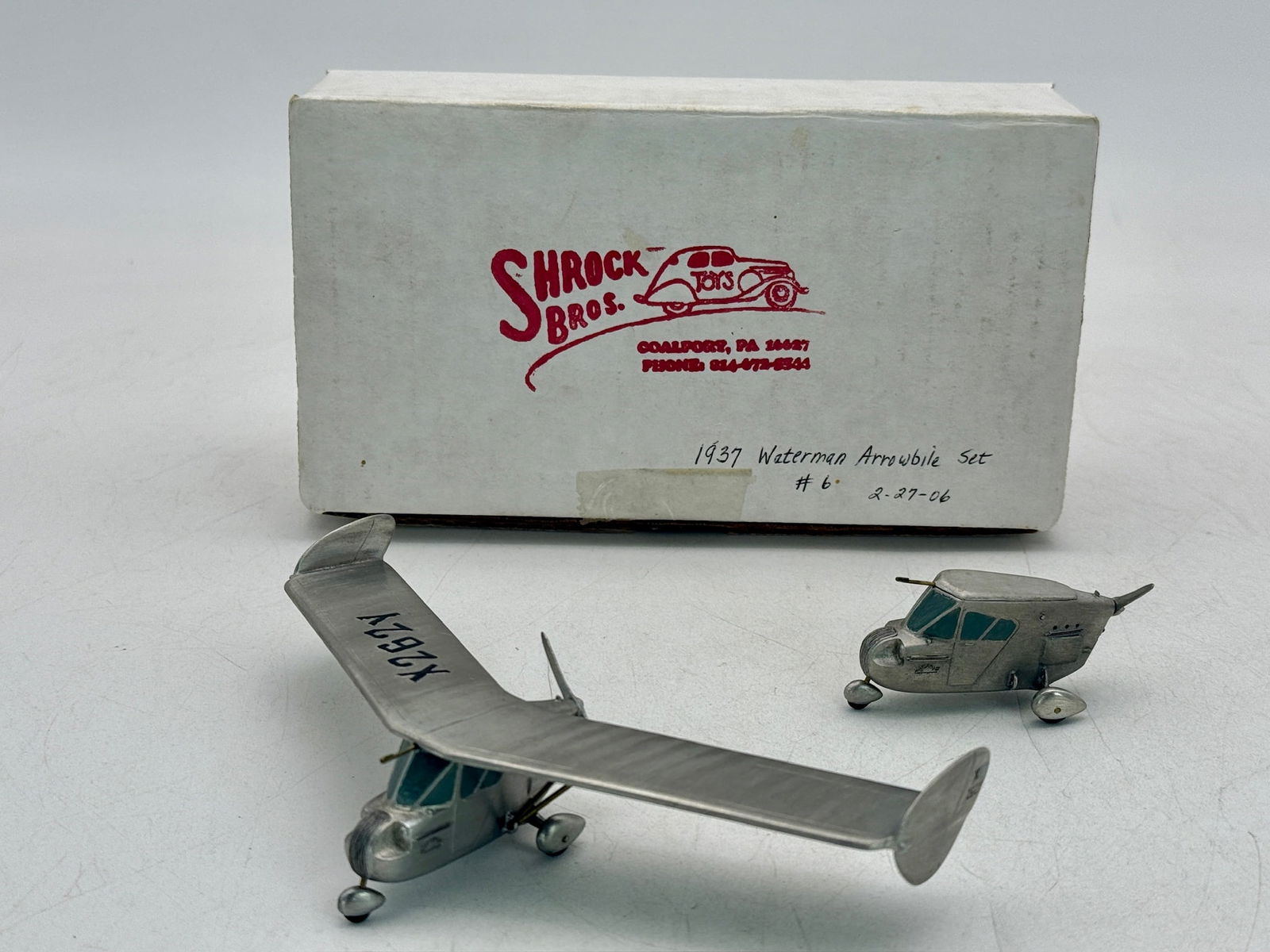 Shrock Bros. Toys 1937 Waterman Arrowbile Set: A silver-colored miniature set featuring a cabin unit and a 6.5" wingspan, winged aircraft marked X262Y, accompanied by the original Shrock Bros. OB. C9