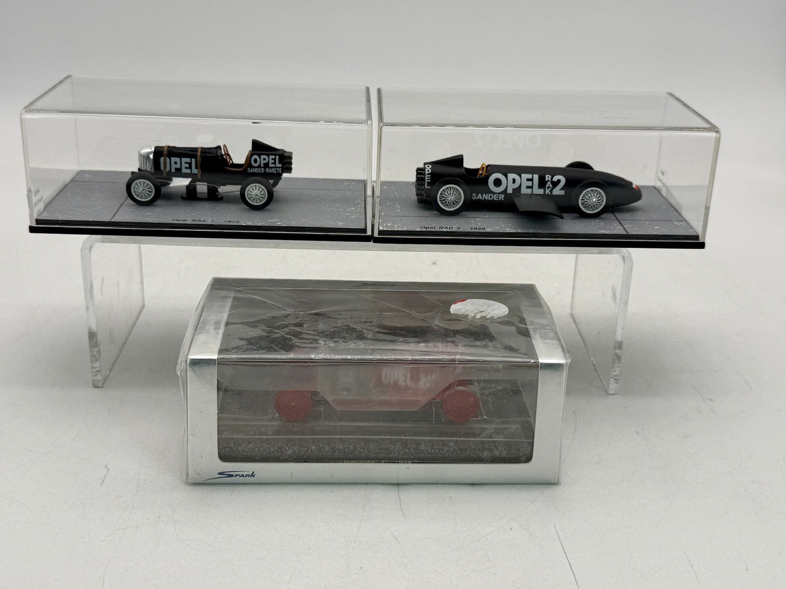 3 Spark Opel RAK Scale Model Rocket Racers: 3 Spark scale resin model rocket vehicles including the black Opel RAK 1 50820 and RAK 2 cars 50821 and the red Opel RAK 3 50822 rail vehicle, all from 1928 and housed in original display cases. OBS m