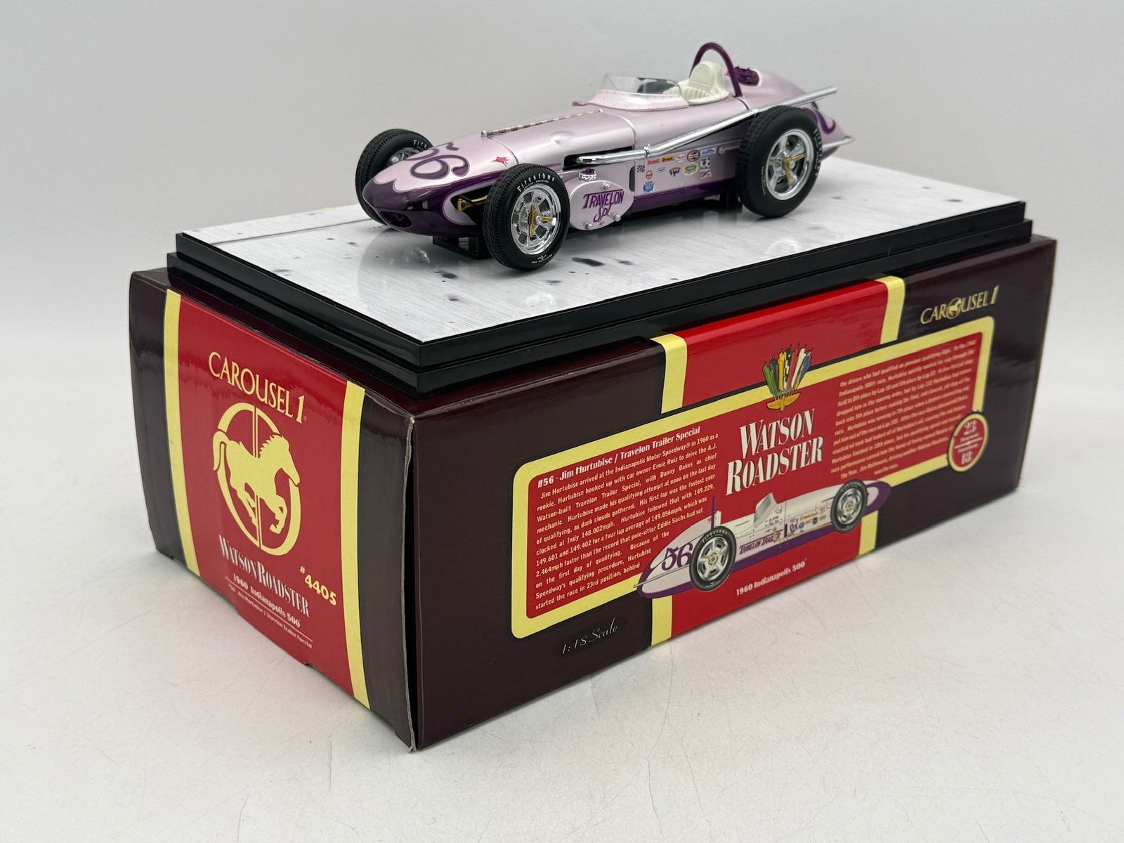 Carousel 1 4405 1:18 1960 Watson Roadster Jim Hurtubise #56: A 1:18 scale die-cast Watson Roadster model car in lavender and purple featuring number 56 and Travelon Trailer Special livery, including original packaging and certificate of authenticity. 9 inches l