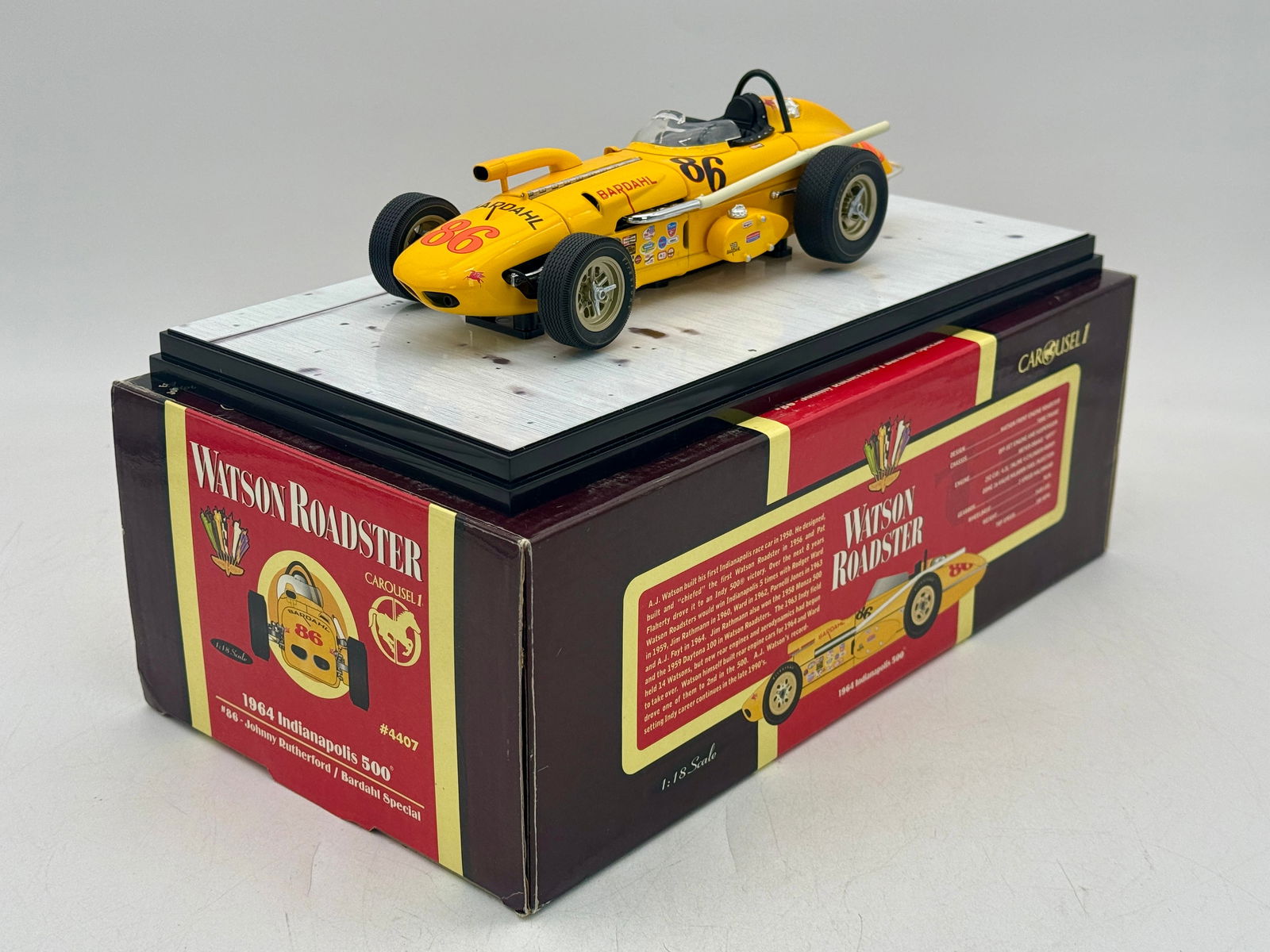 Carousel 1 1:18 4407 Johnny Rutherford 1964 Watson Roadster #86: A yellow 1:18 scale die-cast model of the #86 Bardahl Special Watson Roadster driven by Johnny Rutherford in the 1964 Indianapolis 500, including original packaging and certificate of authenticity. 9