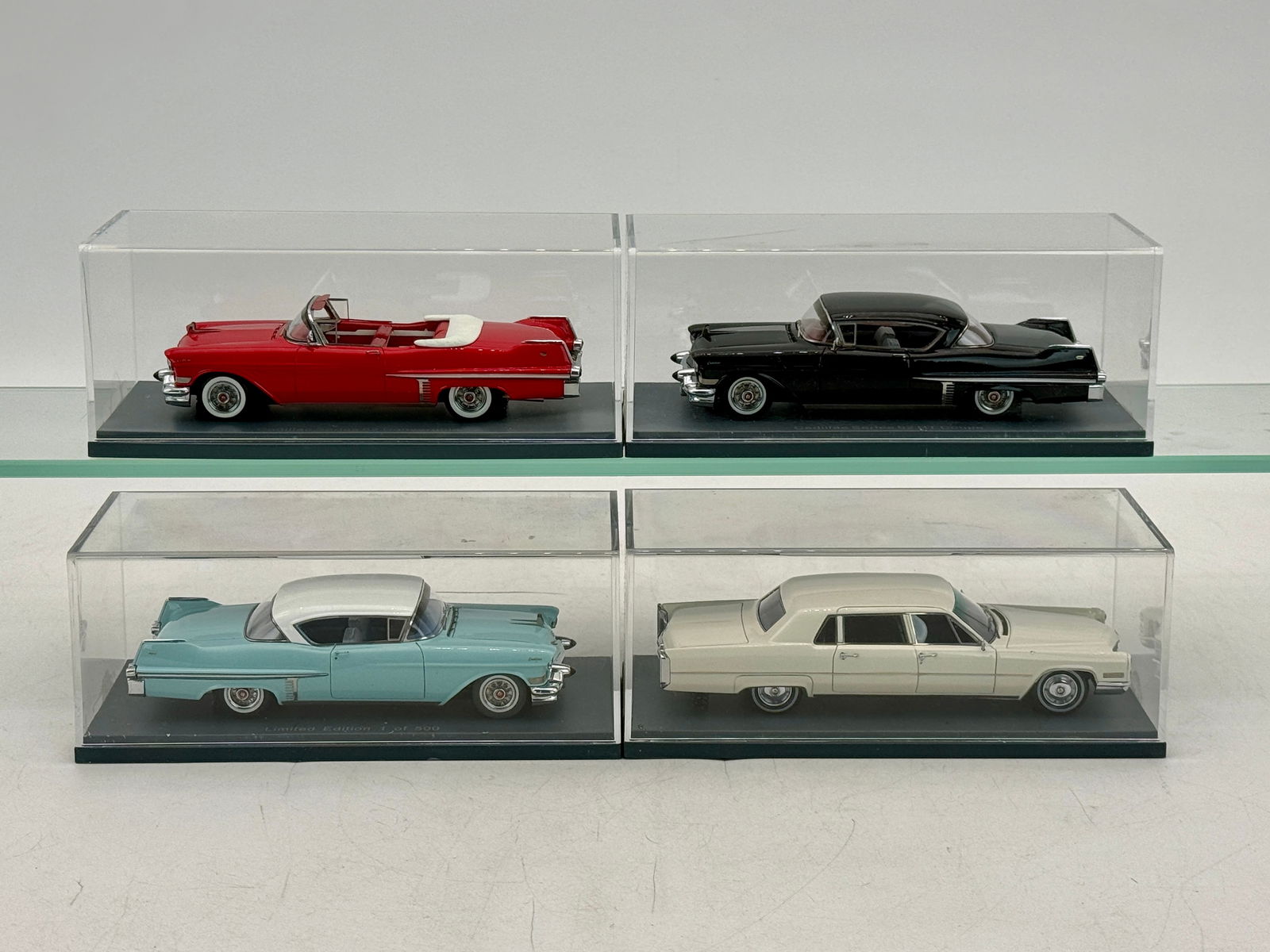 A Collection of 4 Cadillac Die-Cast Model Cars: A collection of Cadillac die-cast model cars in red, black, light blue, and off-white, resin, 1:43 scale including a Cadillac Series 62 HT Coupe, a Limited Edition 1 of 500, and a Cadillac Fleetwood S
