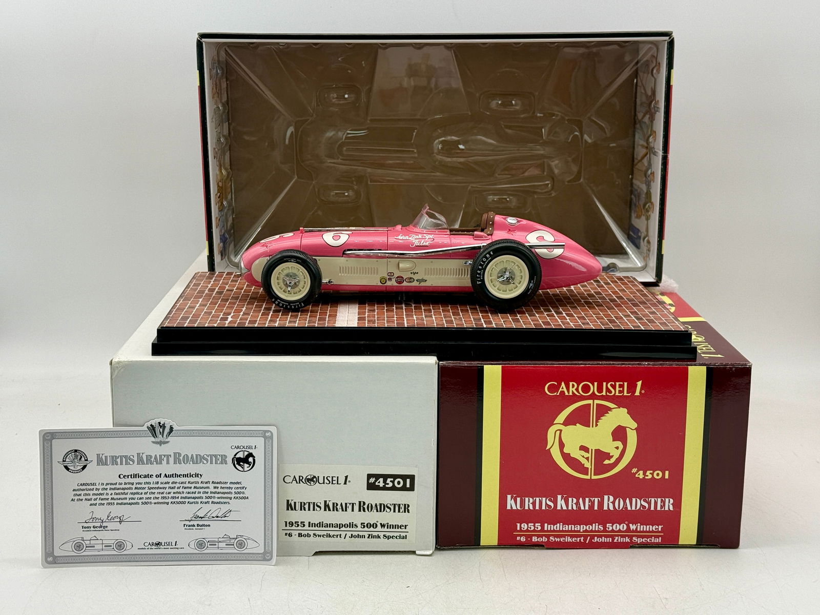 Carousel 1 #4501 1:18 Kurtis Kraft Roadster: A pink and cream 1/18 scale Carousel 1 #4501 Kurtis Kraft Roadster die-cast model of the 1955 Indianapolis 500 winner driven by Bob Sweikert, including several original boxes and a certificate of