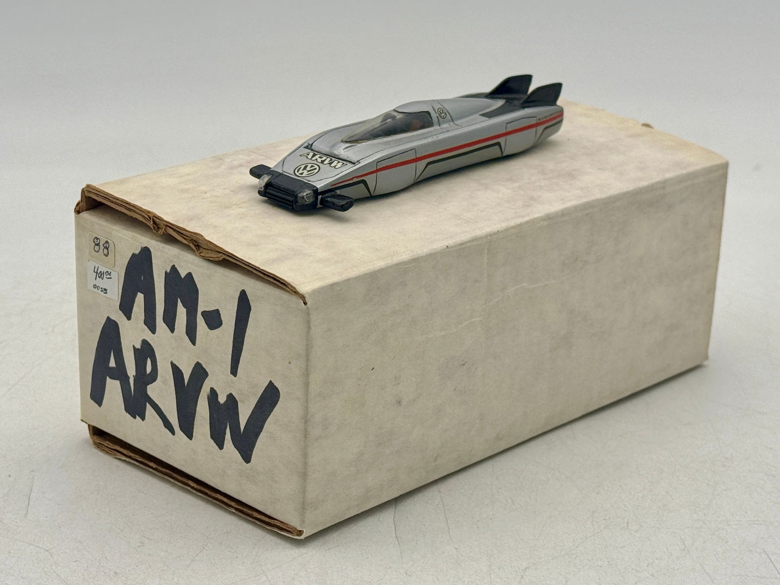 AM-1 Silver Arvus Record ARVW Model Car: A silver Volkswagen ARVW toy car featuring red and black accents and the Volkswagen logo, accompanied by a white storage box marked AM-1 ARVW. Resin, 4.75" long, OB C9.