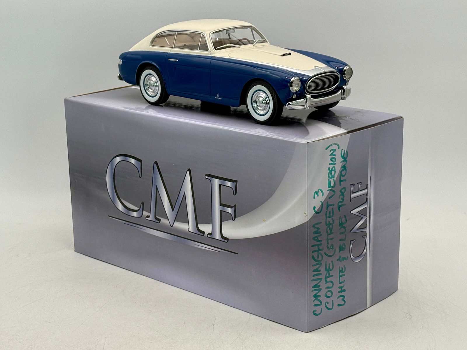 CMF 18025 1:18 Cunningham C3 Vignale Sports Coupe Model Car: A 1:18 scale model of a Cunningham C3 Vignale Sports Coupe street version featuring a blue and white two-tone finish with its original CMF storage box, 128 of 300, 10 inches long, C9.