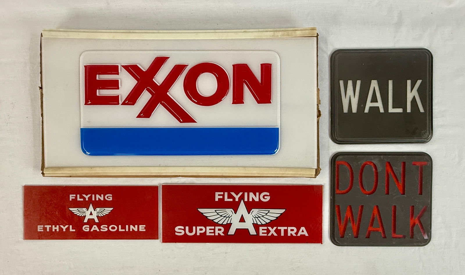 A Collection of Vintage Exxon and Flying A Gasoline Signs: A collection of vintage advertising and signal inserts including an embossed plastic Exxon sign, two Flying A gasoline panels for Ethyl and Super Extra, and two pedestrian signal inserts reading Walk