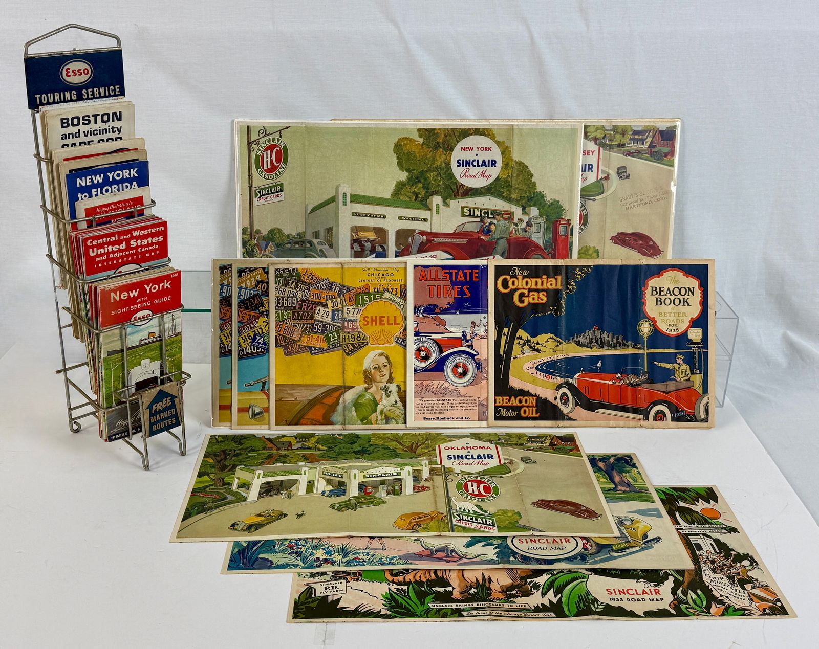 A Collection of Vintage Road Maps and Travel Ephemera: A large assortment of multi-colored vintage road maps and travel ephemera from brands including Esso, Sinclair, Shell, Texaco, and Atlantic, accompanied by a metal Esso Touring Service display rack C5