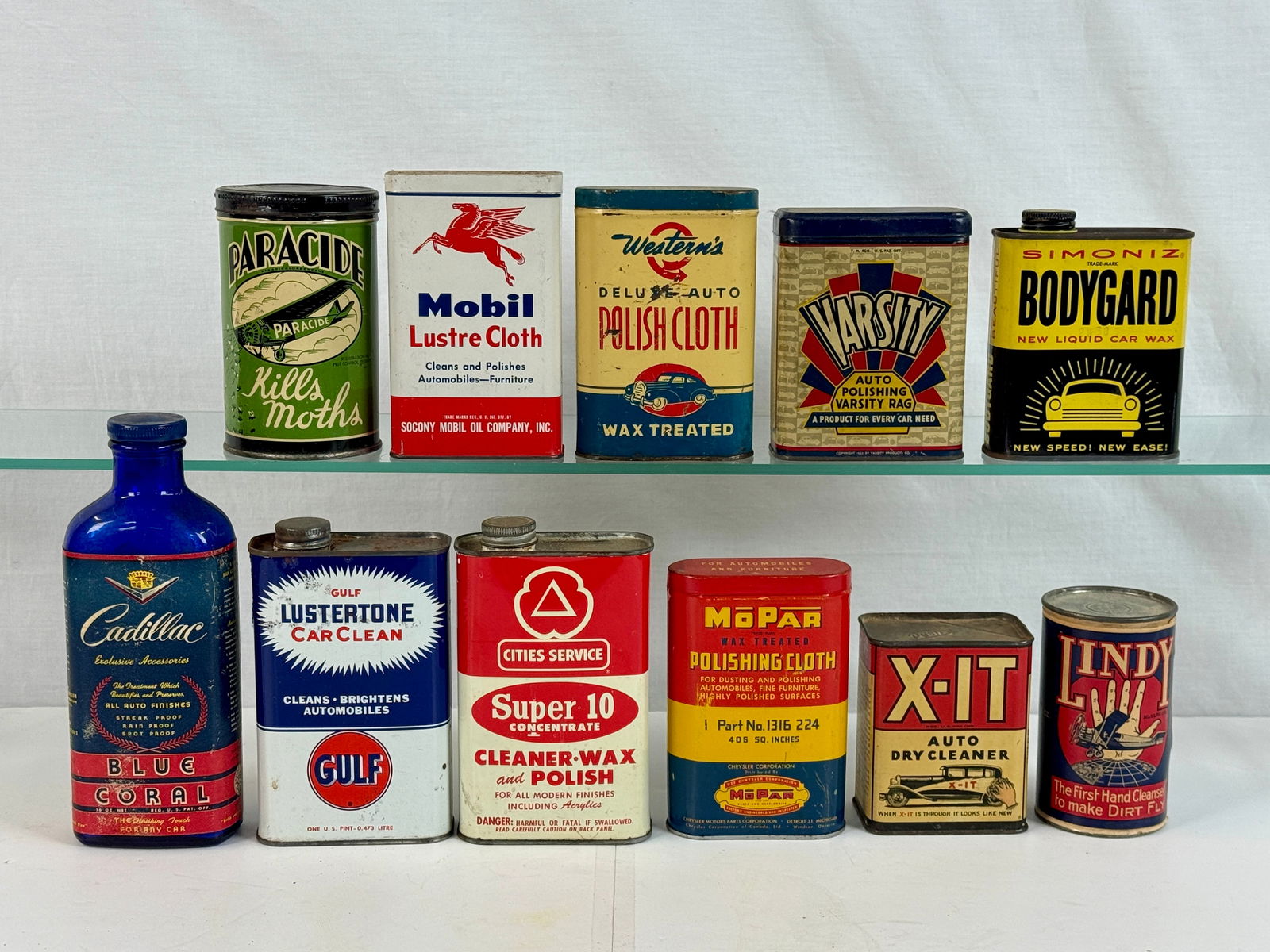 A Collection of Vintage Automotive and Household Maintenance Containers: A collection of vintage automotive and household maintenance containers including a cobalt blue Cadillac Blue Coral bottle and various tins from brands such as Mobil, Gulf, Simoniz, and MoPar C 5-8.