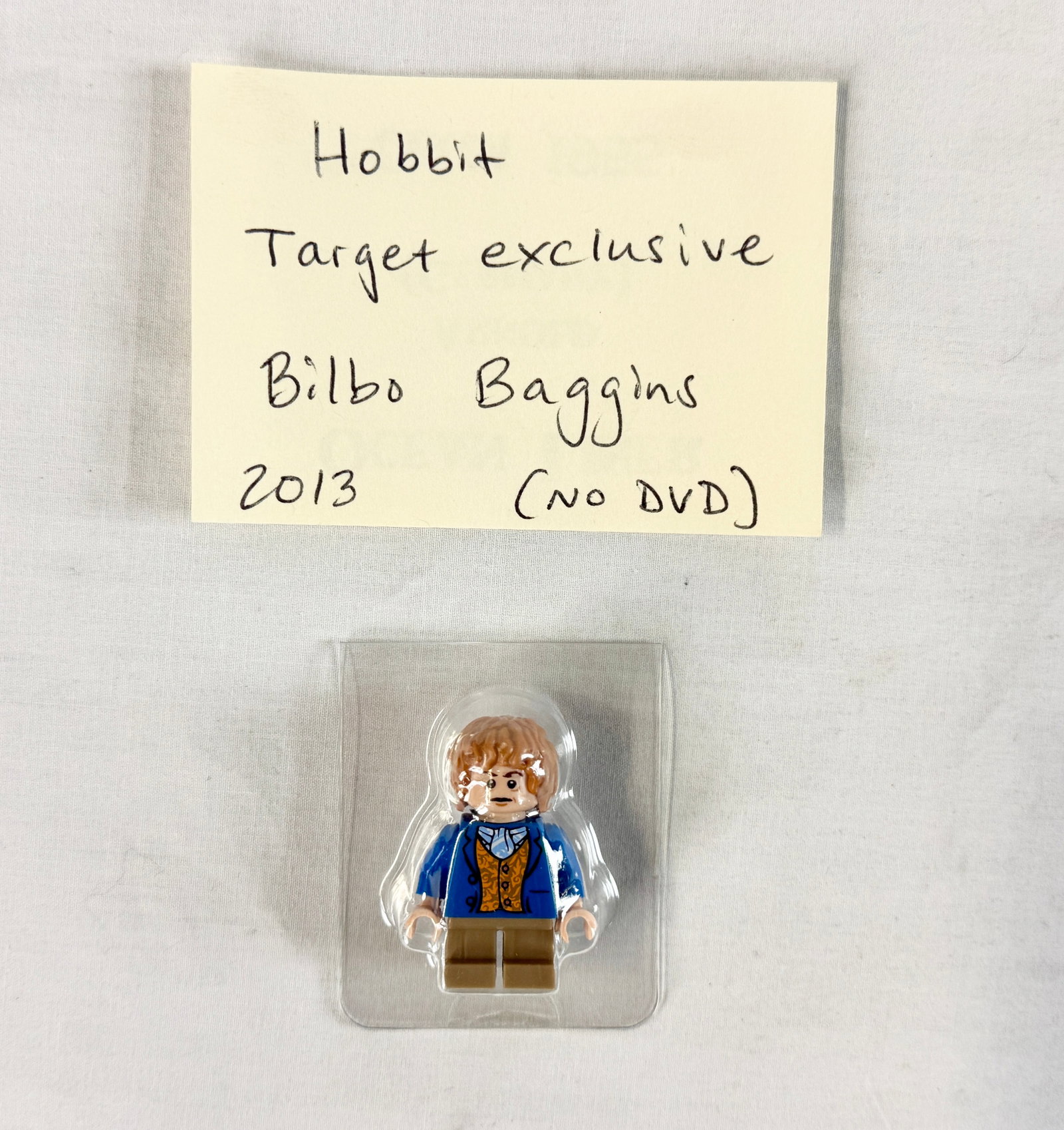 LEGO Bilbo Baggins Blue Coat Minifigure The Hobbit Target Exclusive: This LEGO minifigure depicts the character Bilbo Baggins from The Hobbit film trilogy. The figure features the character wearing a blue jacket over an ornate orange and gold patterned waistcoat with a