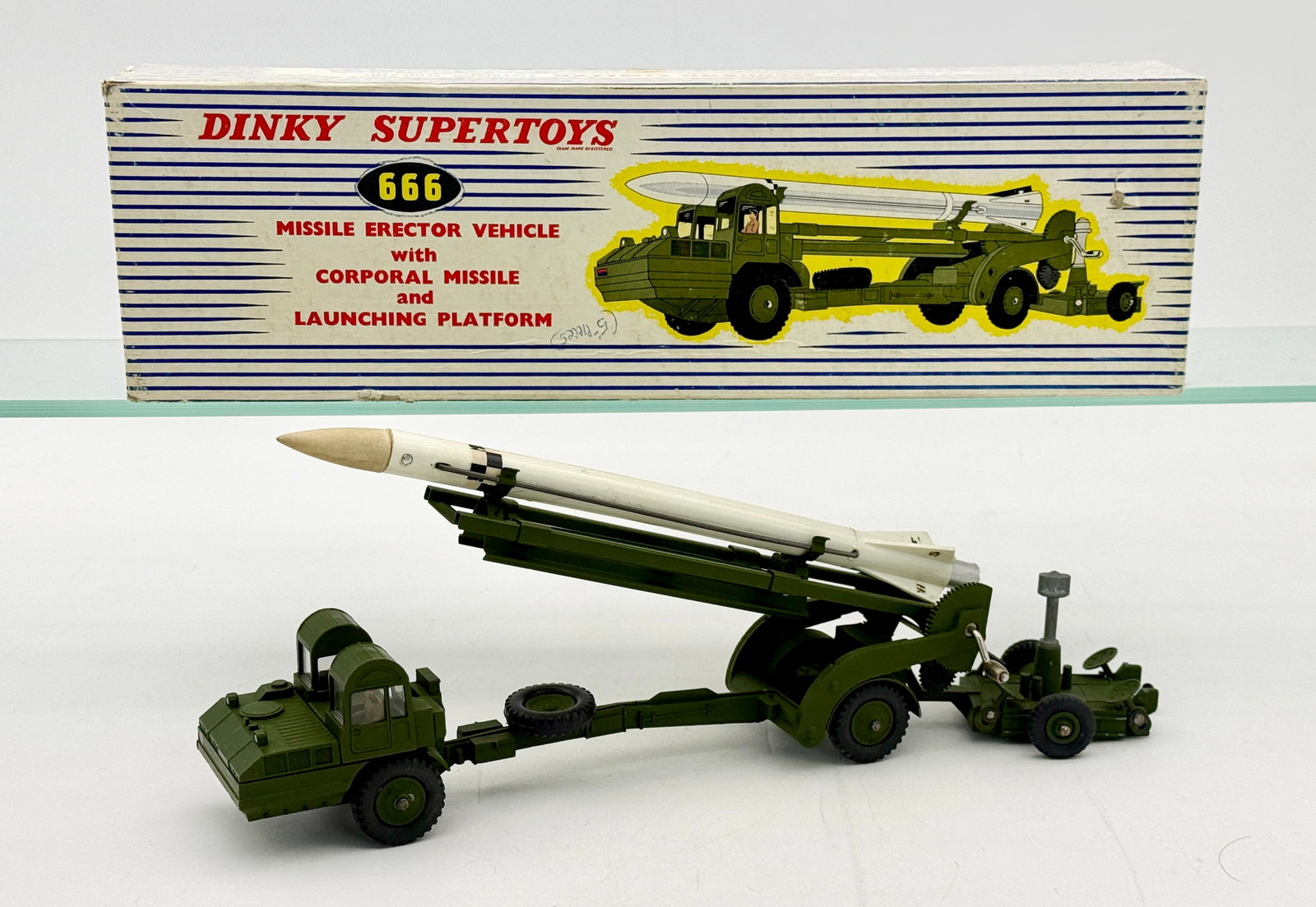 Dinky Supertoys No. 666 Missile Erector Vehicle and Original Box: Dinky Supertoys No. 666 Missile Erector Vehicle set featuring die-cast metal and plastic construction. The olive drab vehicle includes a gear-driven mechanism and detachable launching platform paired 