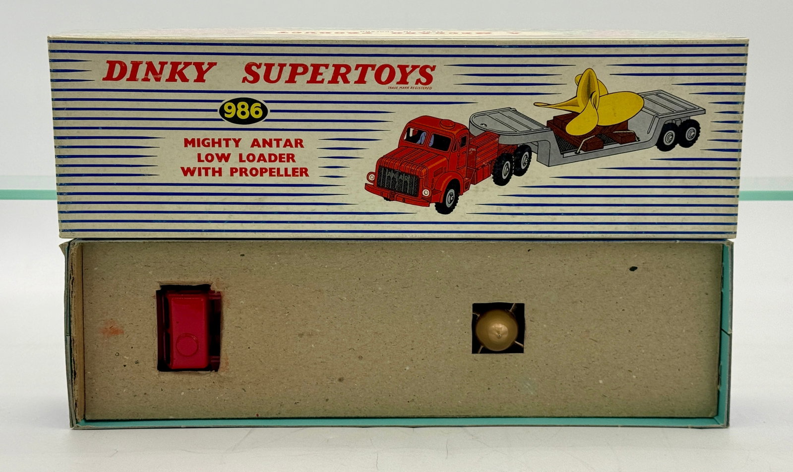 Dinky Supertoys No. 986 Mighty Antar Low Loader with Propeller: Manufactured by Meccano Ltd., this die-cast Mighty Antar vehicle set includes a red tractor unit and a grey low-loader trailer. The set features a gold-toned plastic marine propeller load with a Scimi