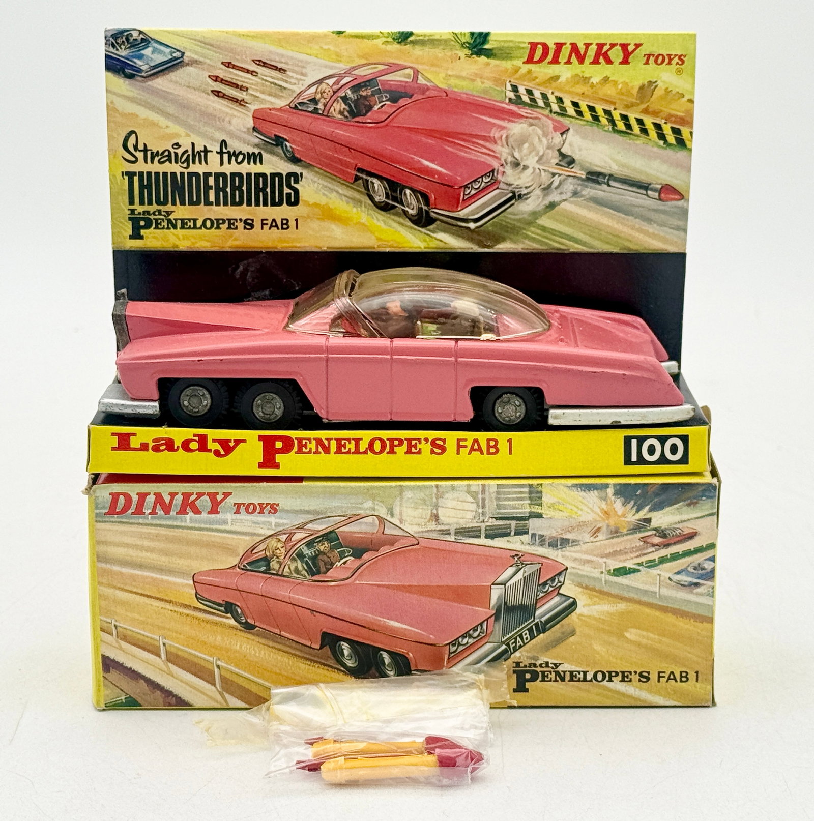 Dinky Toys 100 Lady Penelope's FAB 1 Thunderbirds Model Car: This Dinky Toys No. 100 die-cast model features a pink finish and is based on the FAB 1 vehicle from the Thunderbirds television series. The car includes six wheels, a clear sliding canopy with interi