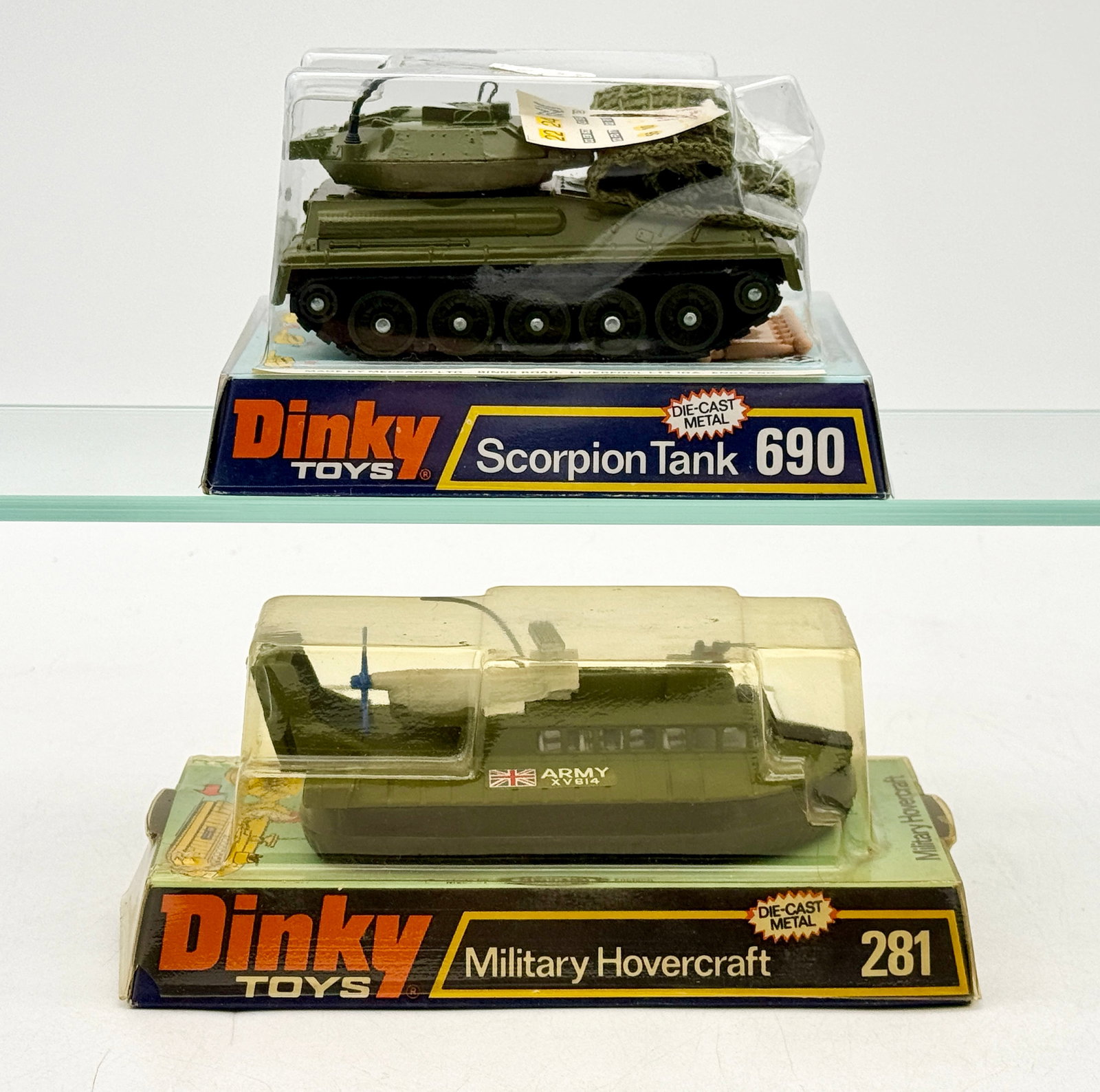 Two Dinky Toys Die-Cast Military Vehicles in Original Packaging: Dinky Toys military vehicles including a 690 Scorpion Tank and a 281 Military Hovercraft, both finished in olive green die-cast metal. The tank features a removable camouflage net accessory while the 
