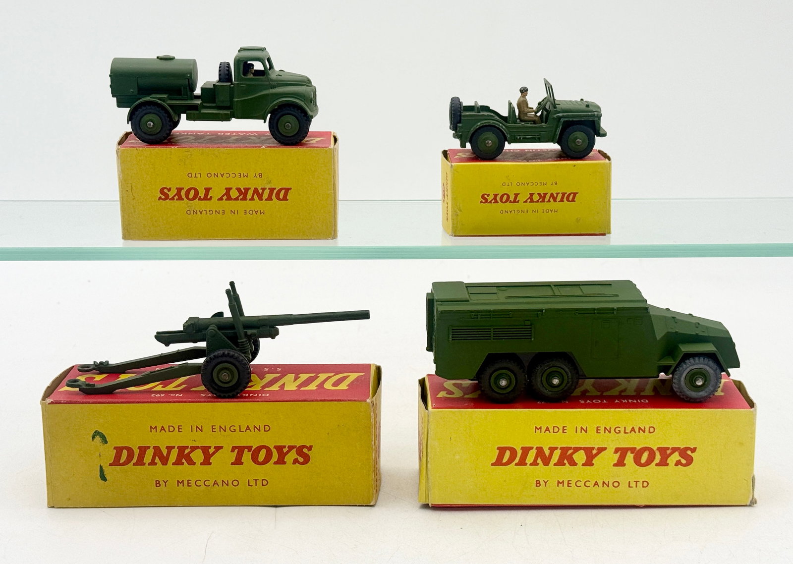 A Collection of Dinky Toys Die-Cast Military Vehicles and Boxes: Dinky Toys die-cast military models manufactured in England by Meccano Ltd. This collection includes an Army Water Tanker, an Austin Champ with driver figure, a 5.5 Medium Gun, and an Armored Command 