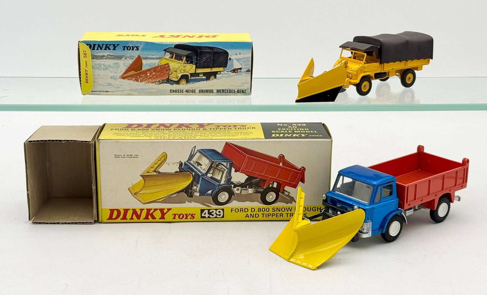 Two Dinky Toys Snow Plough Trucks with Original Boxes: This pair of vintage die-cast model trucks by Dinky Toys includes a French-made Mercedes-Benz Unimog and an English-made Ford D.800. The Mercedes-Benz No. 567 is finished in yellow with a black textur