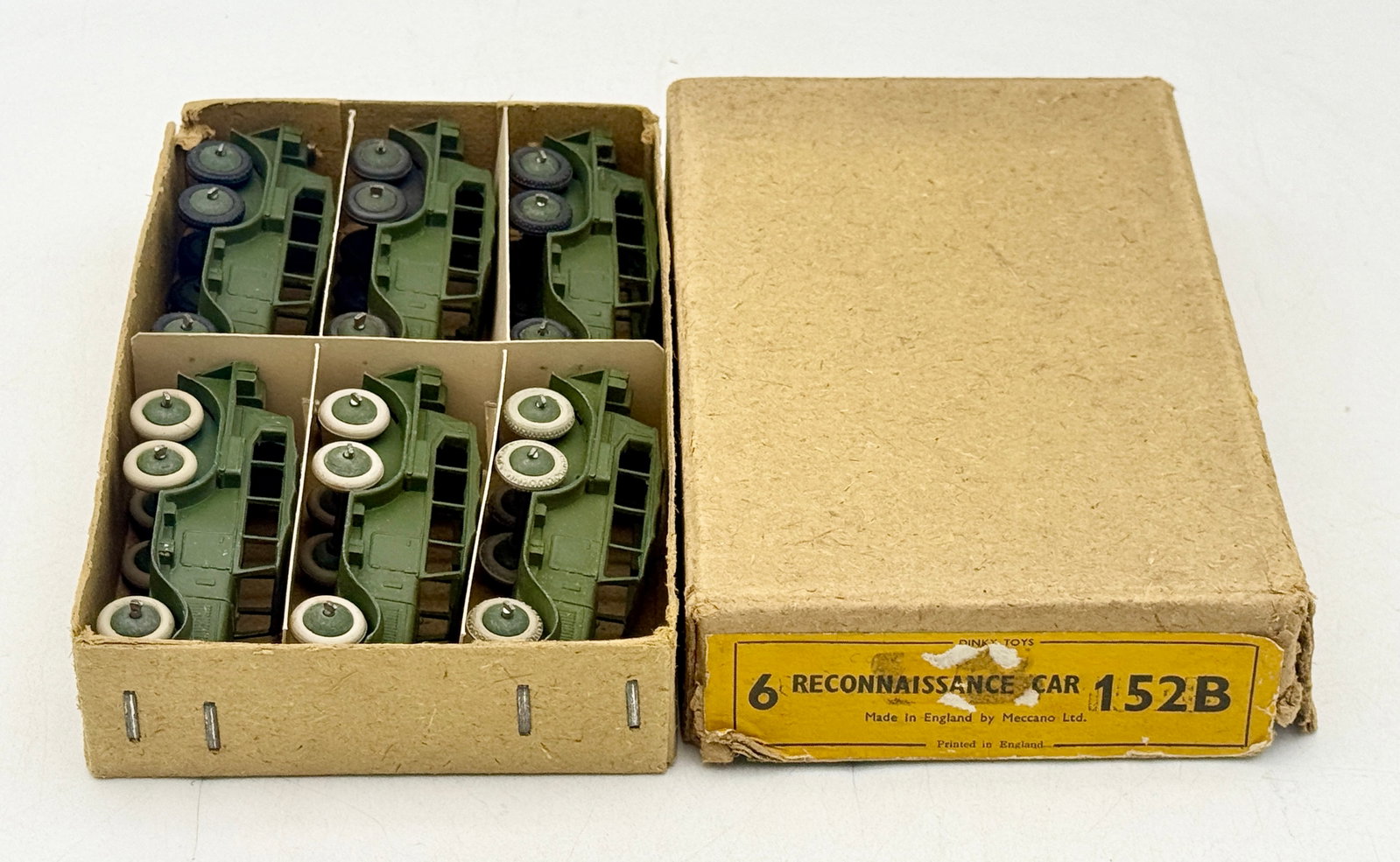 6 Dinky Toys 152B Reconnaissance Cars with Trade Box: A collection of Dinky Toys 152B Reconnaissance Cars manufactured by Meccano Ltd. in England. Each die-cast vehicle is finished in olive drab green and features either cream or dark grey wheels. The se