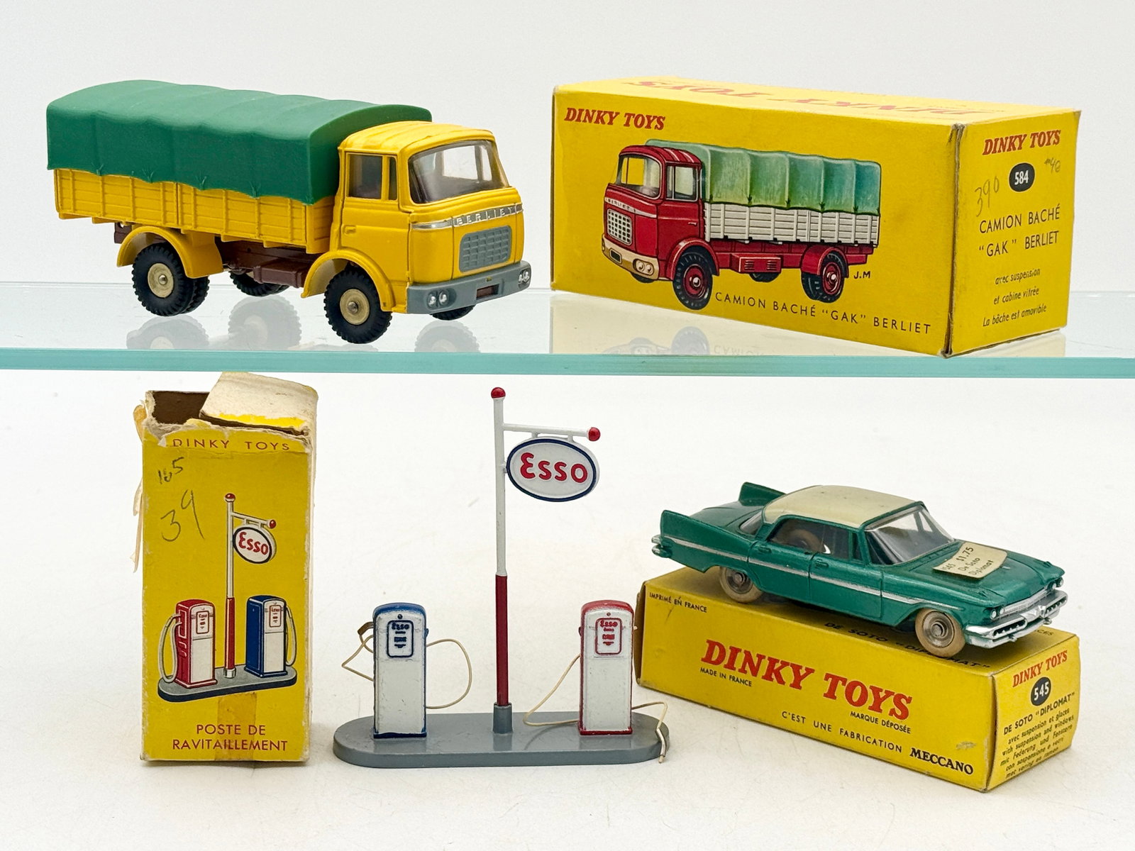 A Trio of French Dinky Toys Die-Cast Vehicles and Accessories: A trio of vintage die-cast metal Dinky Toys produced by Meccano in France, complete with their original yellow cardboard boxes. The collection features a No. 584 Berliet GAK covered truck in yellow wi